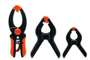 Black and orange spring clamp isolated on white background. Set of small, medium, and big size of plastic clamp. Clamping tools for carpentry work. Hand tools for handicraft. Clamping equipment. photo