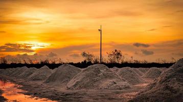 Salt farm in the morning with sunrise sky. Organic sea salt. Evaporation and crystallization of sea water. Raw material of salt industrial. Sodium Chloride. Solar evaporation system. Iodine salt. photo