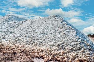 granja de salmuera con cielo azul y nubes blancas. montón de sal marina orgánica cerca del almacén. materia prima de sal industrial. sal del océano viajes de verano en concepto de tailandia. mineral de cloruro de sodio. foto