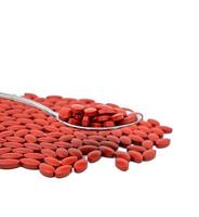 Iron tablets in spoon and spread on white background. Ferrous fumarate for treatment anemia. Blood donations concept. Red tablets pills on  spoon. Pharmacy product. Food for anemia concept. photo