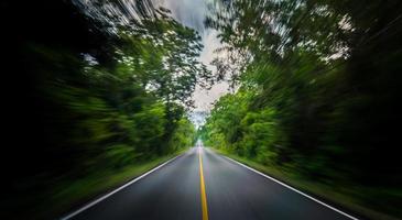 carretera asfaltada vacía y desenfoque de movimiento de velocidad en la carretera en verano con bosques de árboles verdes en el campo foto