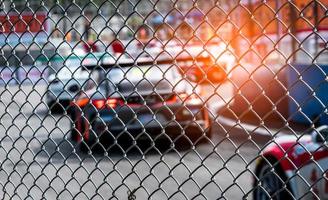 Motor sport car racing on asphalt road. View from the fence mesh netting on blurred car on racetrack background. Super racing car on street circuit. Automotive industry concept. photo