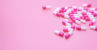 Pink-white antibiotic capsules pill spread on pink background with space. Pharmacy banner. Antibiotic capsule pills. Pharmacy shop wallpaper. Pharmaceutical industry. Antimicrobial drugs. Healthcare. photo