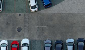 Top view concrete car parking lot. Aerial view of car parked at car parking area of apartment. Outdoor parking space with empty slot. One way traffic sign on road. Above view outside car parking lot. photo