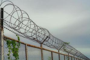Prison security fence. Barbed wire security fence. Razor wire jail fence. Barrier border. Boundary security wall. Prison for arrest criminals or terrorists. Private area. Military zone concept. photo