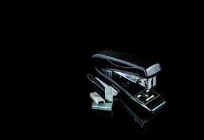 Black stapler and staples on dark background. photo