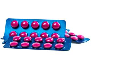 Pink tablets pill in blue blister pack isolated on white background. Painkiller medicine. Pharmaceutical industry. Medicine for treat migraine headache, fever, toothache. Pharmacy drugstore products. photo