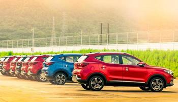 Lujoso vehículo todoterreno rojo, azul y negro estacionado en un área de estacionamiento de concreto en la fábrica cerca de la cerca de la fábrica. Se vende stock de autos. estacionamiento de la fábrica de automóviles. concepto de industria automotriz. concesionario de coches. foto