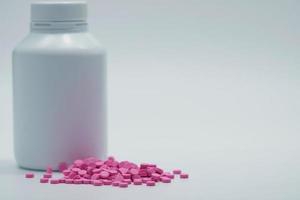 píldoras de tableta rosa con botella de etiqueta en blanco cerrada sobre fondo blanco con espacio de copia. pastilla de tableta de warfarina. medicamento anticoagulante. producto de droguería de farmacia. industria farmacéutica. anticoagulación foto