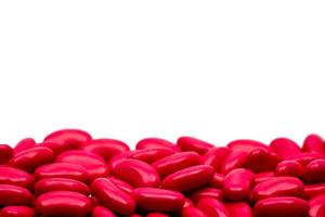 Macro shot detail of red kidney shape sugar coated tablet pills on white background with copy space for text photo