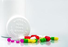 Colorful pills on white background and plastic bottle with blank label and copy space. Childproof packaging. Child resistant pill container. Push down and turn cap.Global healthcare and love concept. photo