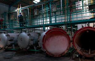 High pressure processing or high hydrostatic pressure machine. Metal tank in food manufacturing factory. Canned food reservoir for sterilizing. Worker working in factory to control pressure of machine photo