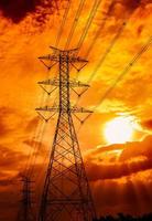 High voltage electric pole and transmission lines. Electricity pylons at sunset. Power and energy. Energy conservation. High voltage grid tower with wire cable at distribution station. Golden sky. photo