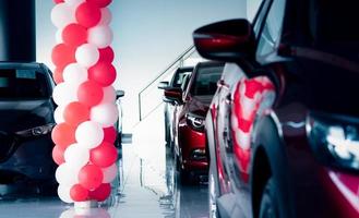 New and shiny luxury SUV car parked in modern showroom with sale promotion events. Car dealership office. Electric car business. Automobile leasing. Automotive industry. Showroom decor with balloons. photo