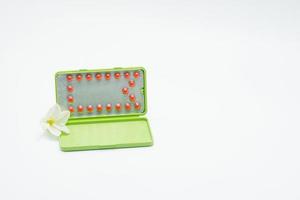 Birth control pills or contraceptive pill with paper case and white flower on white background. Family planning concept. Hormone replacement therapy. Hormonal acne treatment with anti-androgenic pill. photo