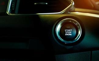 Start stop engine button of luxury car. Push up button for start or stop car engine in keyless automobile. Turn key with ignition system concept. Black ignition switch. Car dashboard interior view. photo