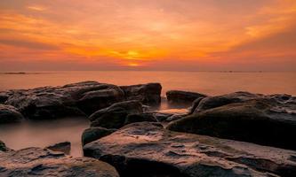 Rocks on stone beach at sunset. Beautiful beach sunset sky. Twilight sea and sky. Tropical sea at dusk. Dramatic sky and clouds. Sunset abstract background. Calm and relax life. Nature landscape. photo