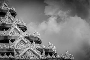 Closeup detail of temple in Thailand. Art pattern. Traditional Thai style sculpture against clouds and sky. Black and white scene of temple detail. Background for sad and death. Buddhist building.