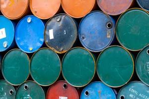 Old chemical barrels. Blue, green, and red oil drum. Steel oil tank. Toxic waste warehouse. Hazard chemical barrel with warning label. Industrial waste in metal drum. Hazard waste storage in factory. photo