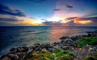 rocas en la playa de piedra al atardecer. hermoso cielo de puesta de sol en la playa. crepúsculo mar y cielo. mar tropical al atardecer. cielo dramático y nubes. calma y relaja la vida. paisaje de la naturaleza. concepto tranquilo y pacífico. foto