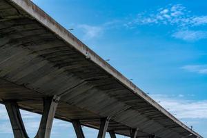 Bottom view of elevated concrete highway. Overpass concrete road. Road flyover structure. Modern motorway. Transportation infrastructure. Concrete bridge engineering construction. Bridge architecture. photo