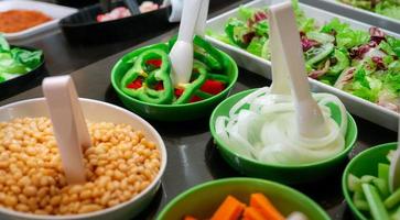 Salad bar buffet at restaurant. Fresh salad bar buffet for lunch or dinner. Healthy food. Green and red pepper and onions in green bowl on counter. Catering food. Banquet service. Vegetarian food. photo