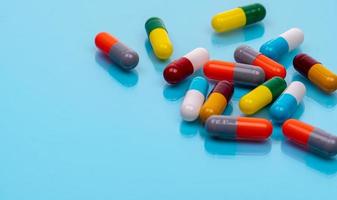 Antibiotic capsule pills on blue background. Prescription drugs. Colorful capsule pills. Antibiotic drug resistance concept. Pharmaceutical industry. Superbug problems. Medicament and pharmacology. photo