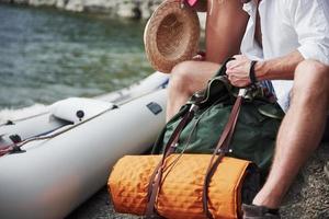 Cute young and couple on river background. A guy and a girl with backpacks are traveling by boat. Traveler summer concept photo