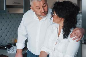hablando de algo hombre y su esposa con camisa blanca preparando comida en la cocina usando verduras