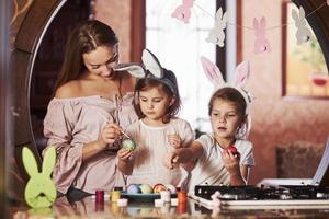 Cute family members. Have happy easter. Two little girls learning how to paint eggs for the holidays photo