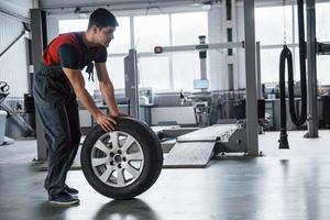 Be right back. Mechanic holding a tire at the repair garage. Replacement of winter and summer tires photo