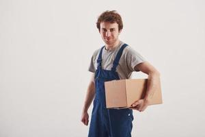 Guy with box in hands stands against white background in the studio photo