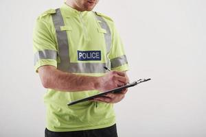 Close up view. Policeman in green uniform stands against white background in the studio photo