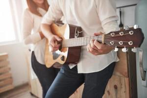 Nice daylight through the window at the morning. Close up view. Guitarist playing love song for his girlfriend in the kitchen photo