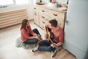 Warm atmosphere. Young guitarist playing love song for his girlfriend in the kitchen photo