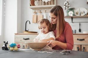 Preparing almost done. Mother teaches daughter to paint the eggs for the Easter holidays photo