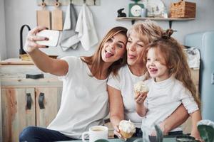 Playing with kid. Mother, grandmother and daughter having good time in the kitchen photo