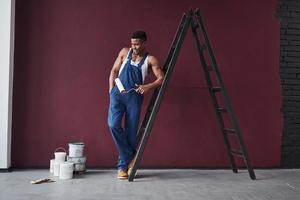 Looks at brushes. Young african american worker in the blue uniform have some job to do photo