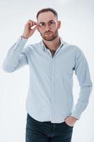 Manager is ready to help. Man in official clothes stands against white background in the studio photo