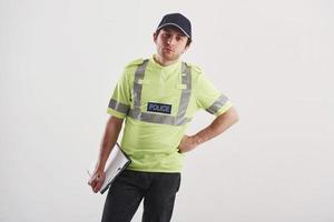 I'm listening to you. Policeman in green uniform stands against white background in the studio photo