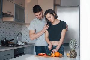 Gente encantadora. pareja joven en la cocina moderna en casa en su tiempo de fin de semana en la mañana foto