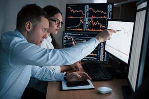 Planning the business project. Team of stockbrokers are having a conversation in a office with multiple display screens photo