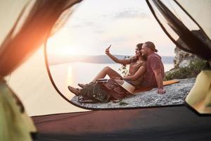 View from tent of couple lying a view of lake during hiking trip. avel Lifestyle concept adventure vacations outdoor photo