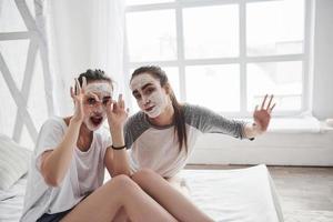 Look at us in that masks. Conception of skin care. Two female sisters have weekend at bedroom photo