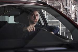 Modern looking guy. Front view of young bearded businessman sitting in his luxury red car photo