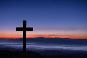 Silhouette of cross on mountain sunrise background. photo