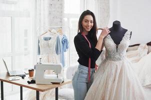 después de un trabajo duro. diseñadora de moda femenina trabaja en la ropa nueva en el taller foto