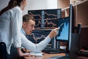 High and nice results. Team of stockbrokers are having a conversation in a office with multiple display screens photo
