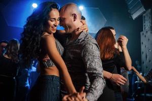 Smiling during the process. Couple dancing at nightime in the club. Enjoying music and each other photo