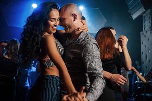 sonriendo durante el proceso. pareja bailando por la noche en el club. disfrutando de la música y el uno del otro foto